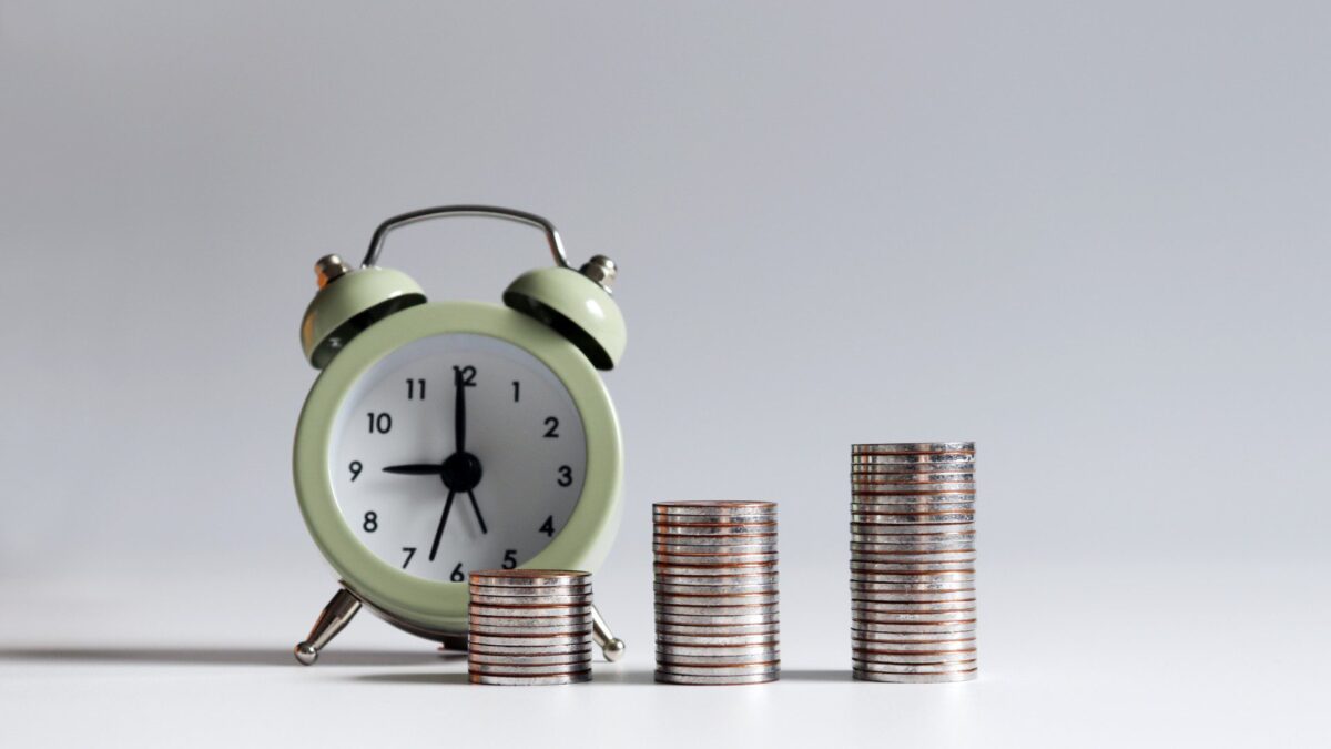an alarm clock sits in front of stacks of coins